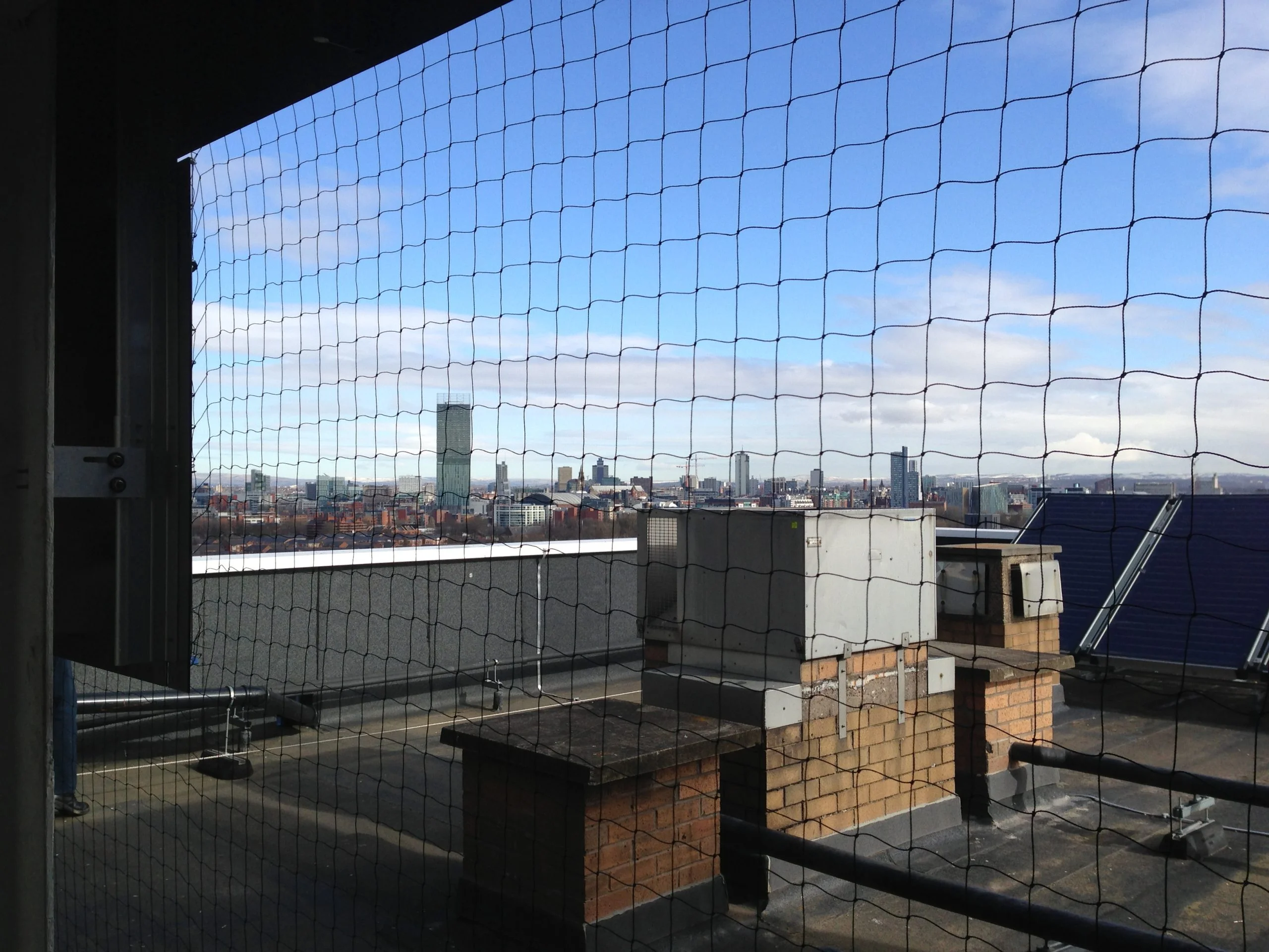 Pigeon netting installed across the flat roof area of a Manchester tower block